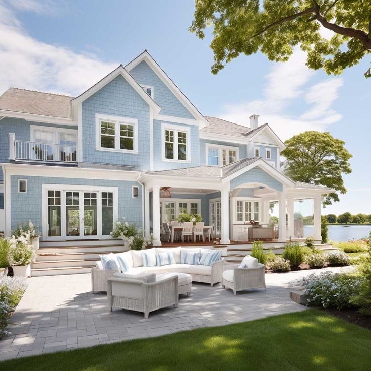 a large blue house with lots of windows and white furniture in front of the house