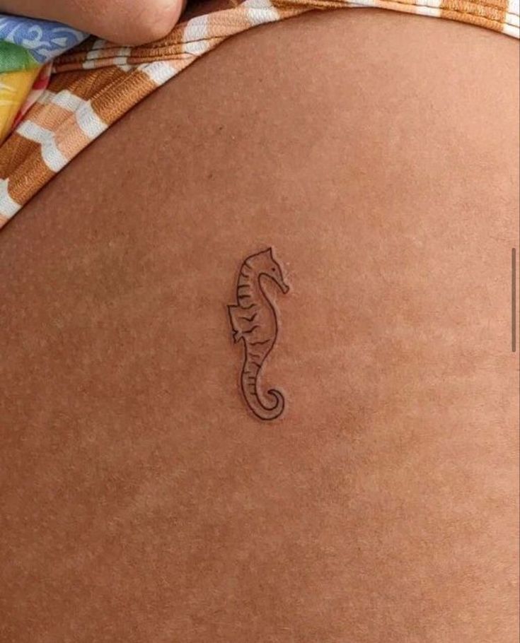 a close up of a person's stomach with a sea horse tattoo on it