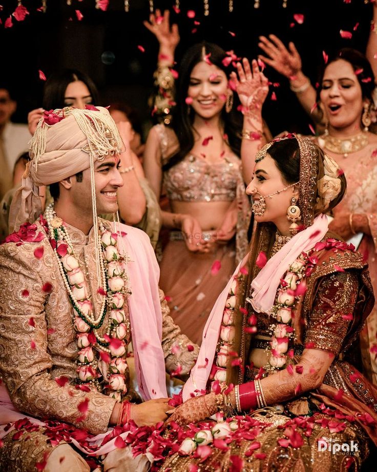 the bride and grooms are surrounded by petals as they sit on the floor in front of their guests