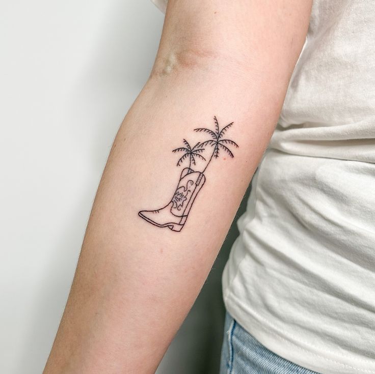 a woman's arm with a tattoo that has a boot and palm trees on it