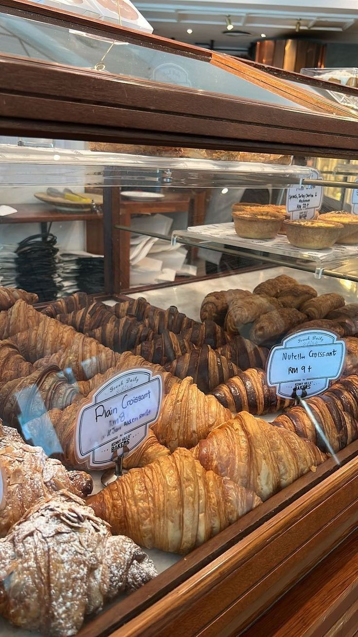 some croissants and other pastries in a display case