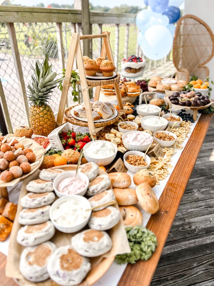 a table filled with lots of food on top of a wooden table next to balloons