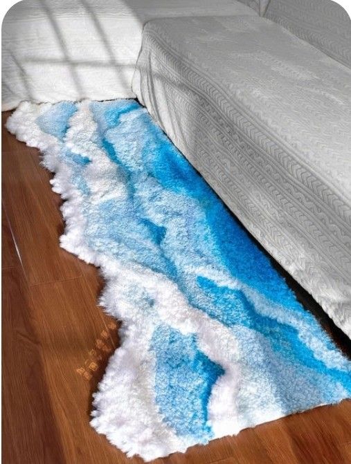 a white bed sitting on top of a wooden floor next to a blue and white rug