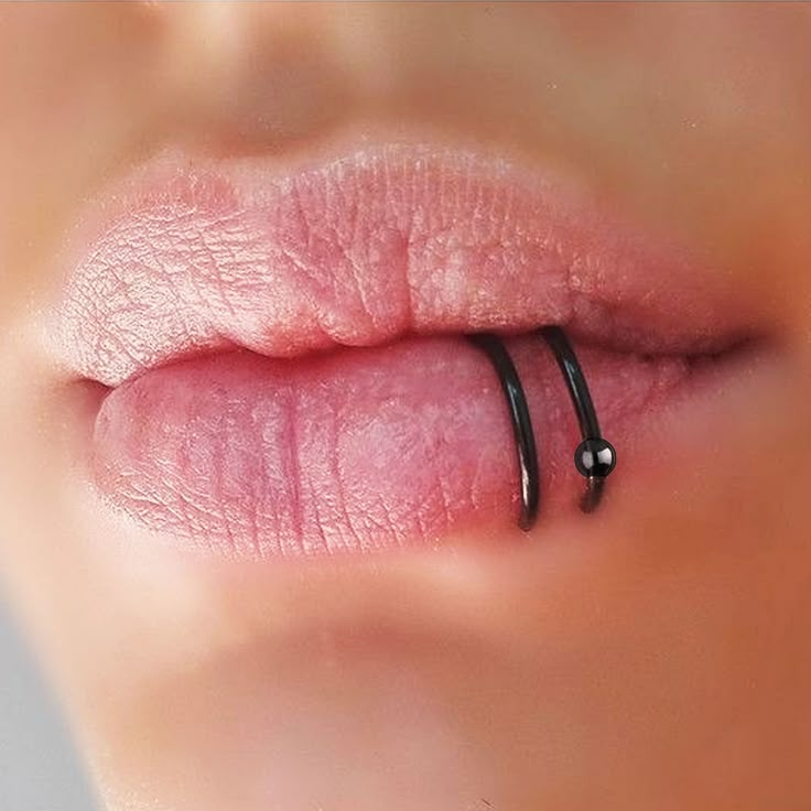 a woman's lip with a thin black ring on top of the lip and her tongue sticking out