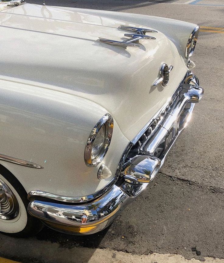 the front end of an old car parked in a parking lot