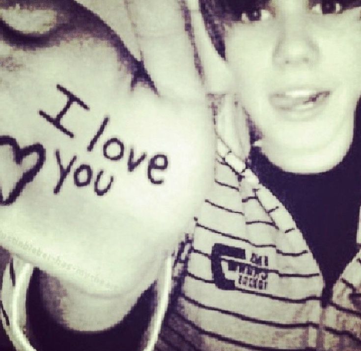 a young boy holding up his hand with the word i love you written on it