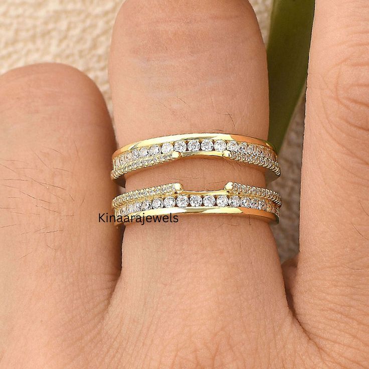 a woman's hand with two gold rings on top of her finger and the ring has three rows of diamonds