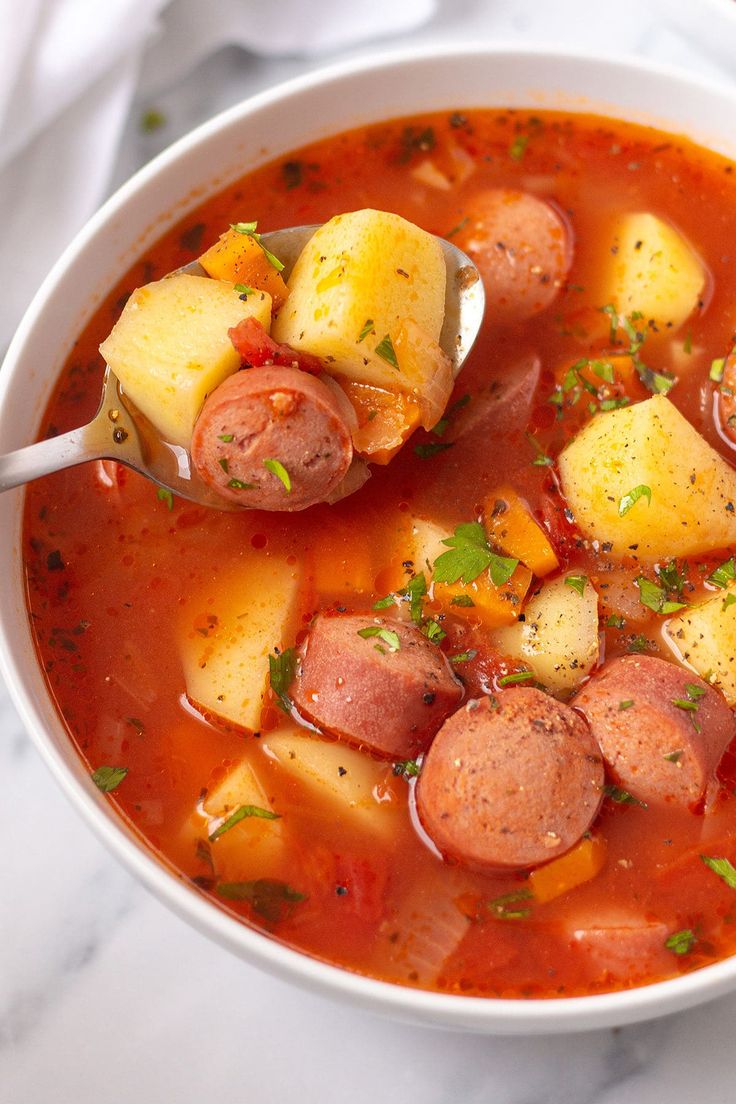 a close up of a bowl of soup with sausage and potatoes