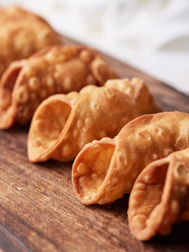 some dumplings are sitting on a wooden cutting board