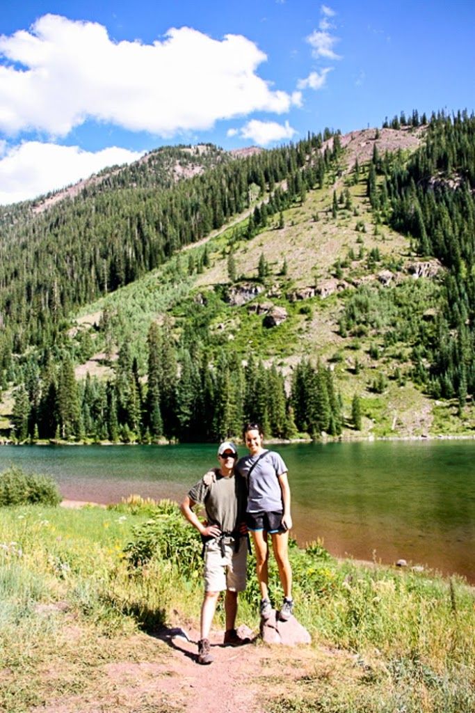 two people standing next to each other near a lake