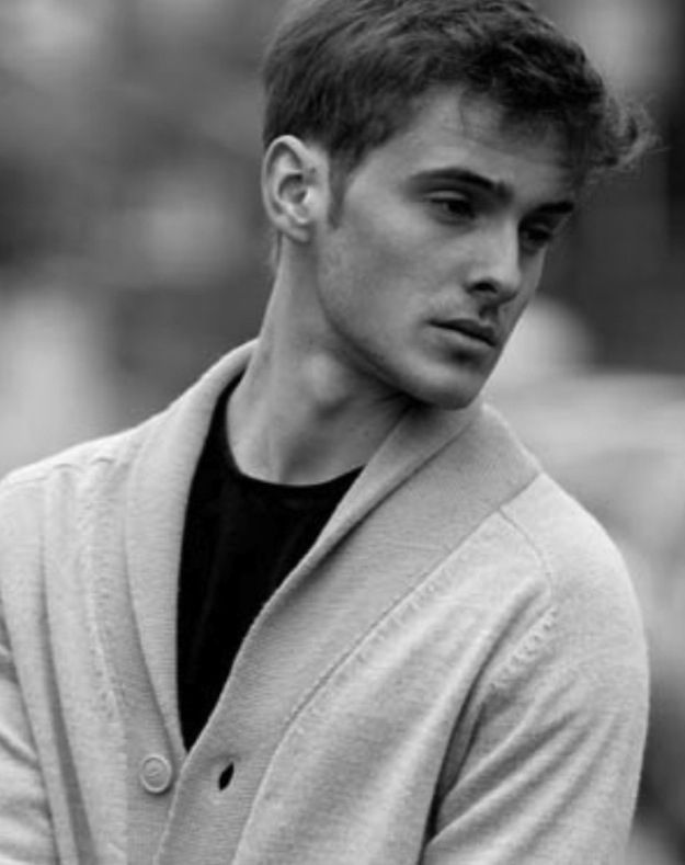 black and white photograph of a young man wearing a cardigan over a t - shirt