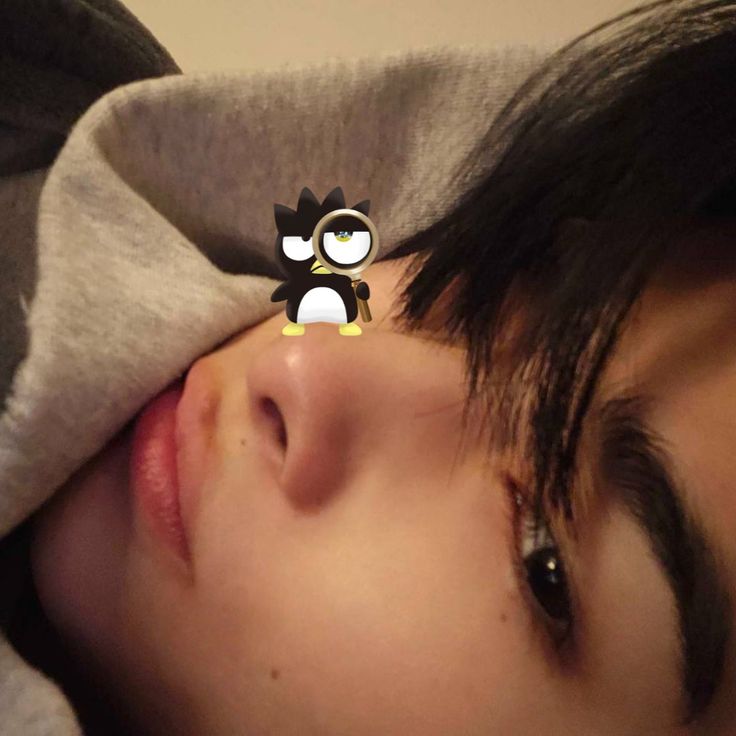 a close up of a person laying in bed with a cat pin on their forehead