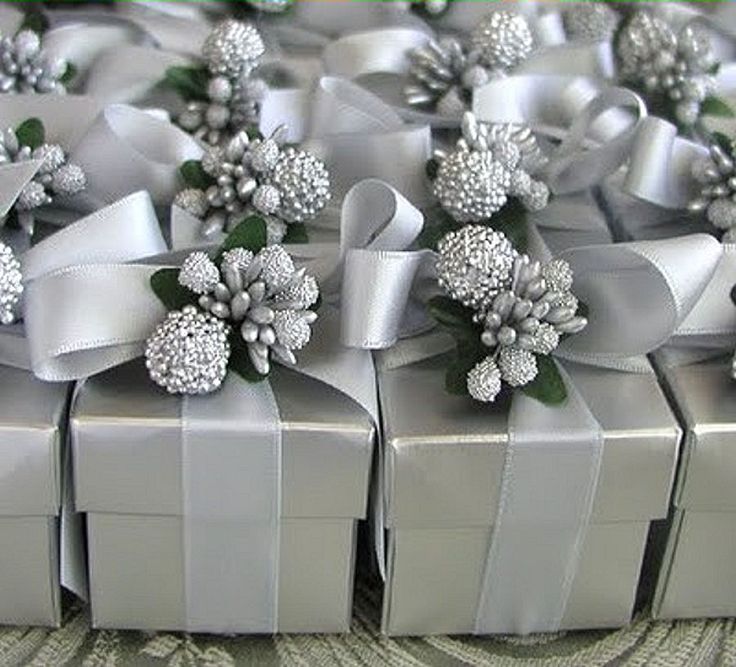 several silver gift boxes with bows and flowers on them