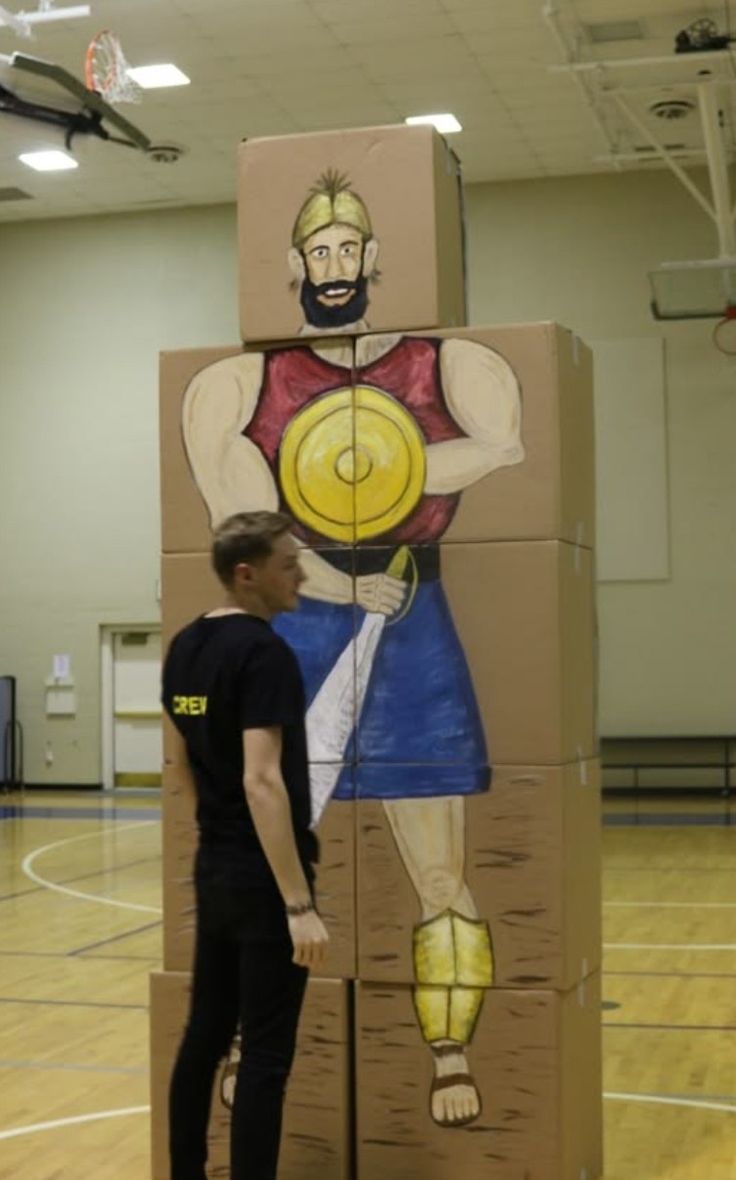 a man standing next to a cardboard box with a painting on it