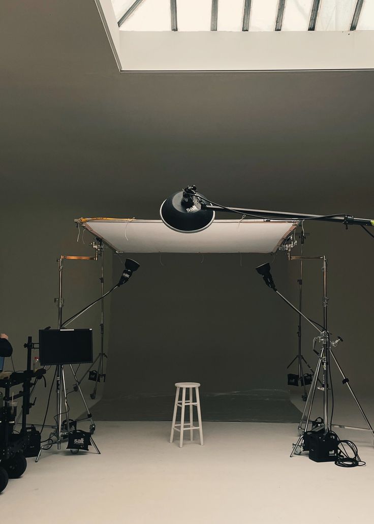 a photo studio with lighting equipment set up in front of a skylight and stool