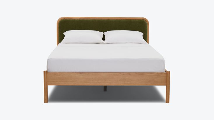 a bed with white pillows and green headboard