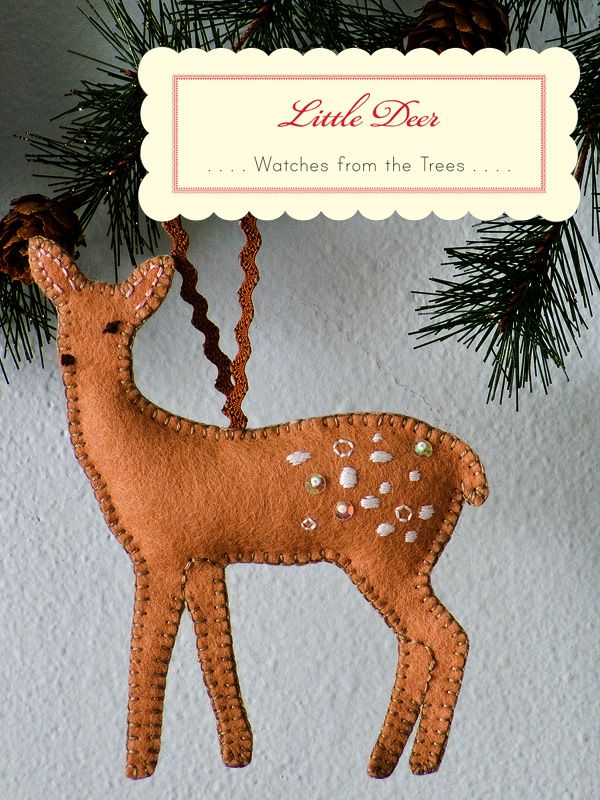 a wooden deer ornament hanging from a pine tree with a card in the background