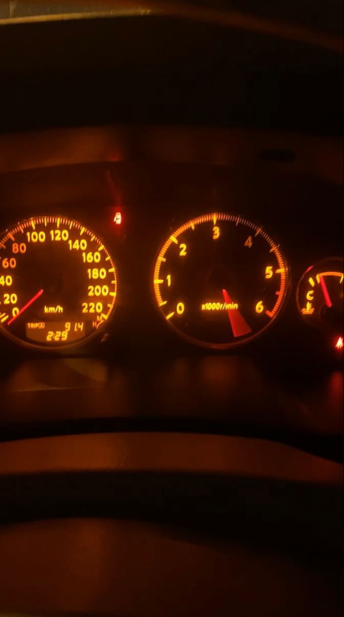 the dashboard of a car is lit up at night