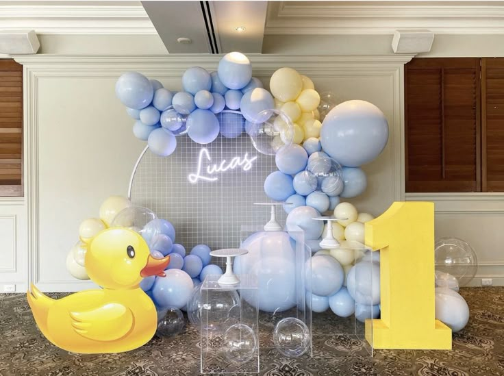 a balloon arch with a rubber ducky next to it and balloons in the shape of numbers