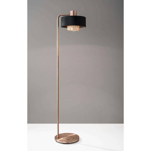 a floor lamp with a black and gold shade on the top, in front of a gray wall