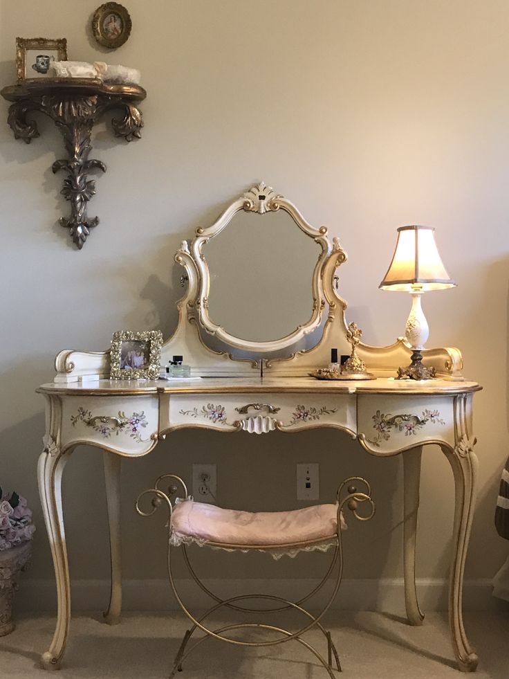 an antique vanity with mirror and stool in a room