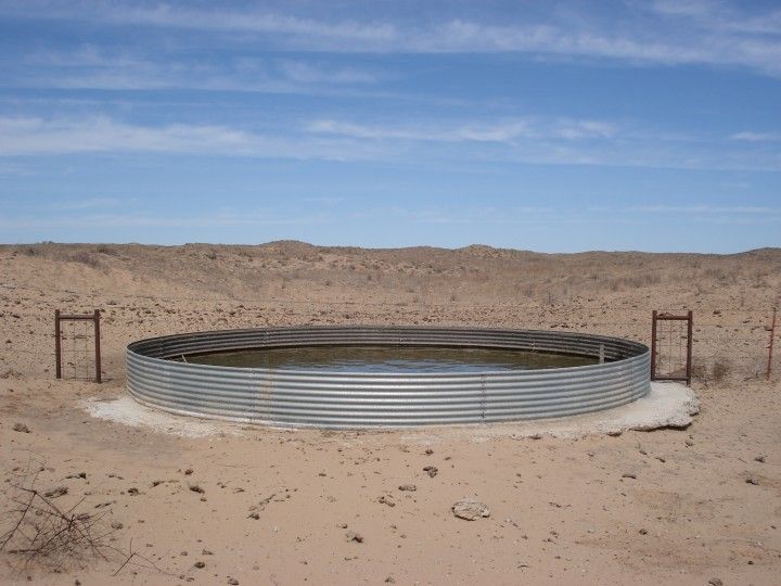 a round metal structure sitting in the middle of a desert area with no people around it