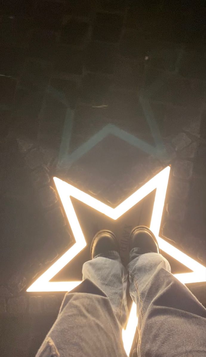 someone standing in front of a star with their feet on the floor and lights shining down