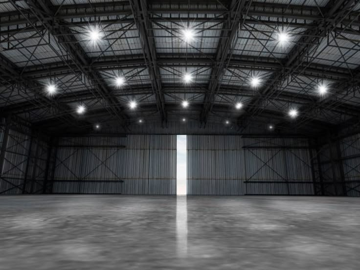 an empty warehouse with bright lights on the ceiling and concrete floor in front of it