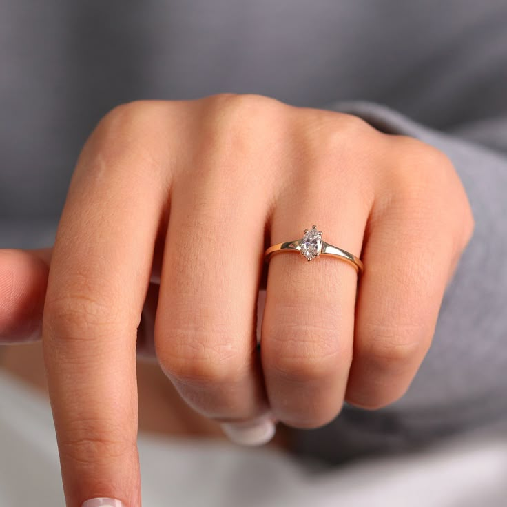 a close up of a person's hand with a diamond ring on their finger