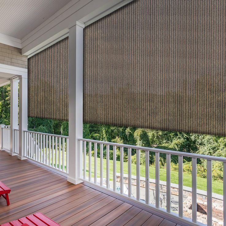 a porch with two red benches on it and a large window covered in brown blinds