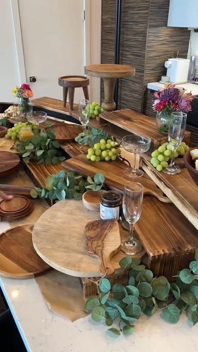 a kitchen counter topped with lots of wooden cutting boards covered in grapes and greenery