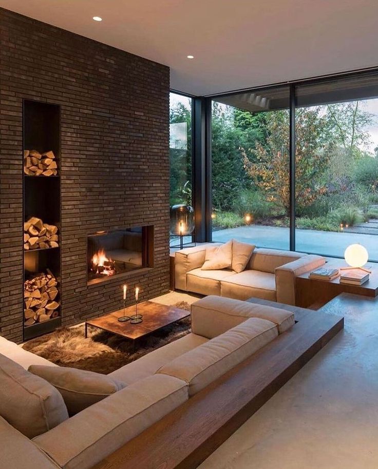 a living room filled with furniture and a fire place in front of a large window