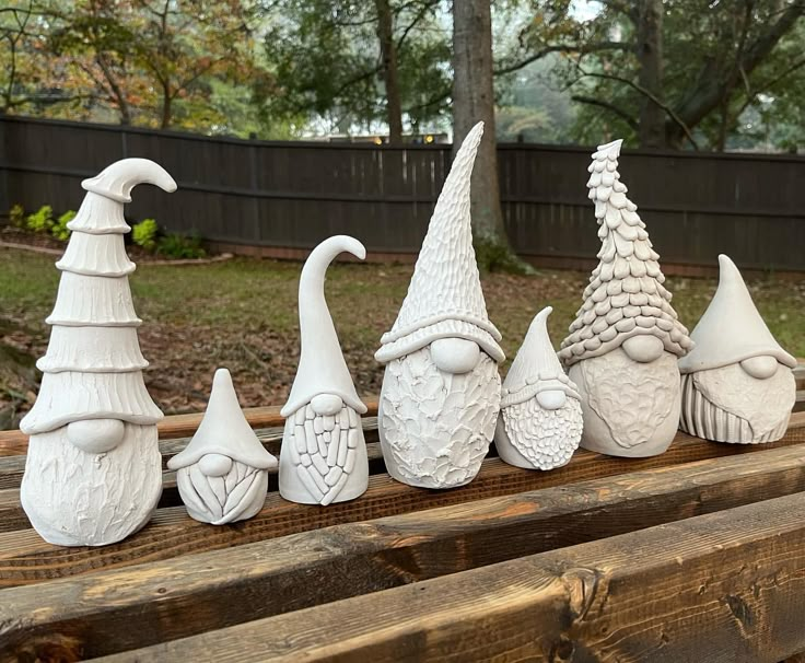 seven white ceramic gnome heads lined up on a wooden bench