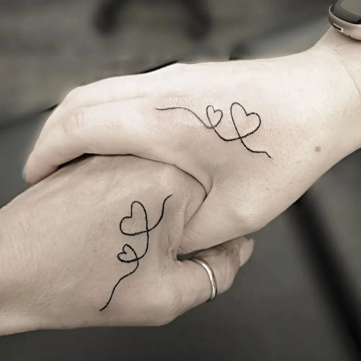 two hands holding each other with small hearts on their fingers and the words love written in black ink