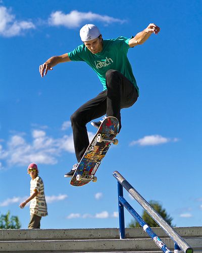 a man riding a skateboard up the side of a metal rail next to stairs