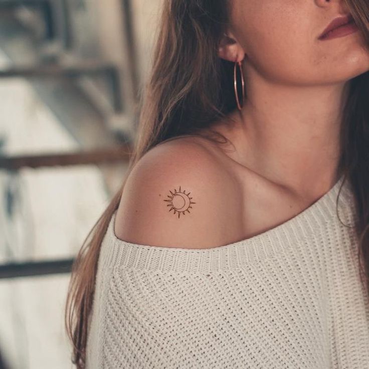 a woman with a small sun tattoo on her shoulder