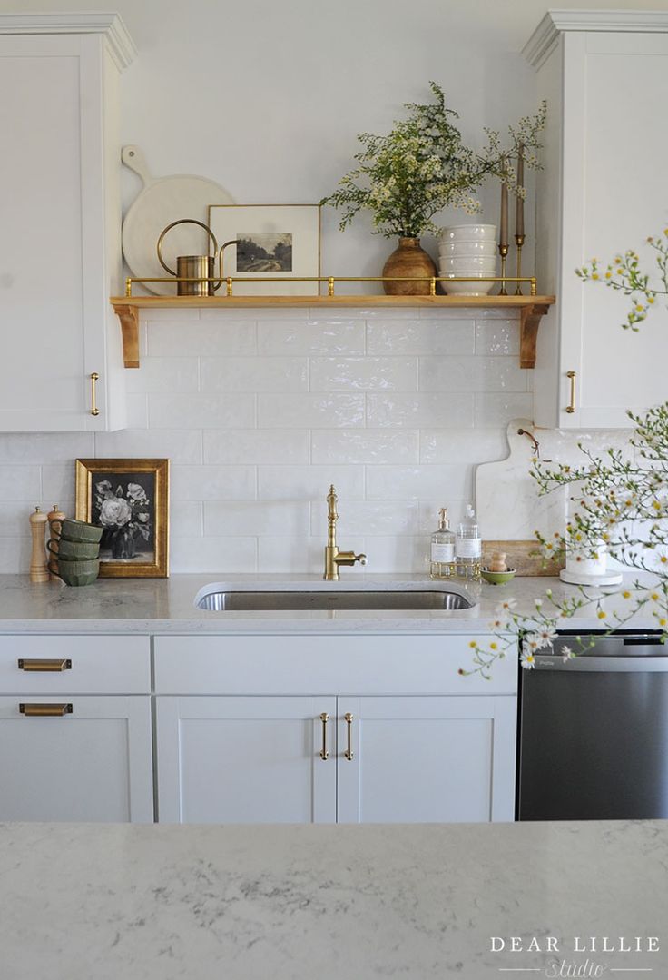 a kitchen with white cabinets and marble counter tops, gold pulls on the cabinet doors