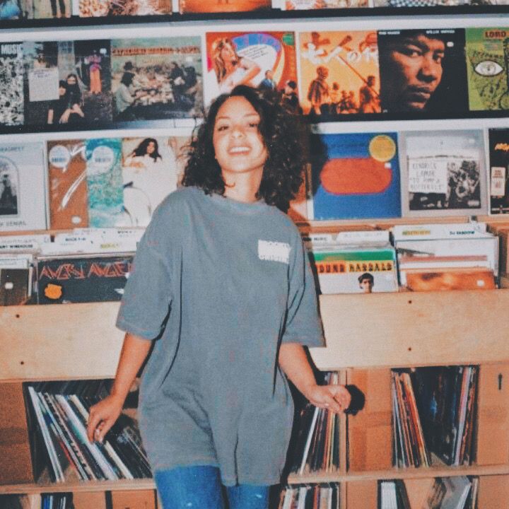 a woman standing in front of a shelf full of records