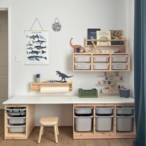 there is a white desk with several bins and toys on the shelf next to it