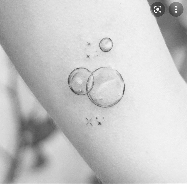 a black and white photo of a person's arm with two bubbles on it