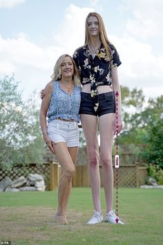 two women standing next to each other in the grass