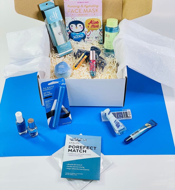 an open box filled with personal care items on top of a blue table cloth next to a cardboard box