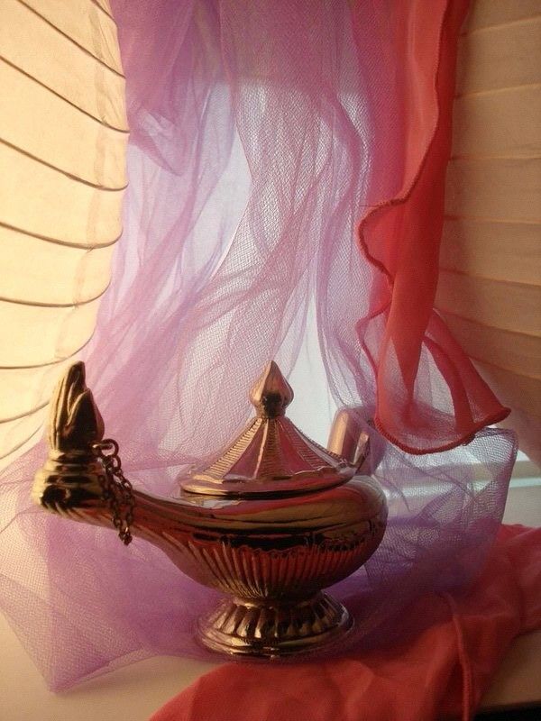 a silver teapot sitting on top of a table next to a red cloth covered window