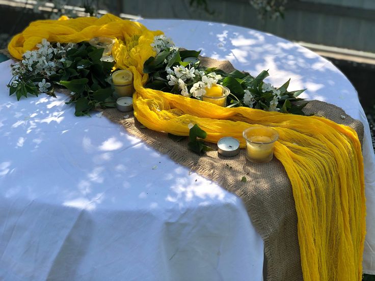 a table with yellow and white flowers on it is set up for an outdoor event