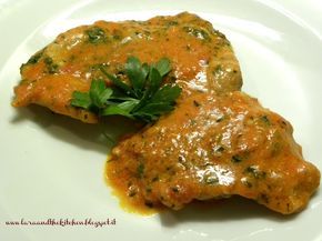 two pieces of meat covered in sauce and parsley on top of a white plate