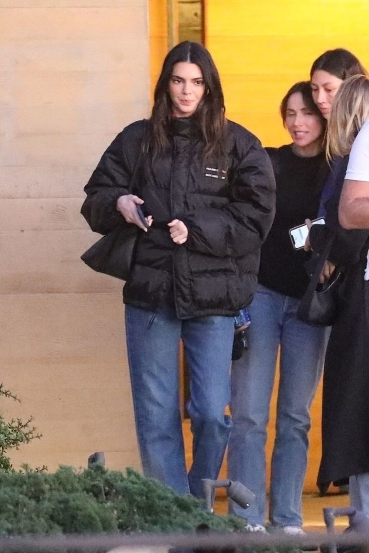 two women are walking down the street with one woman in black jacket and jeans on