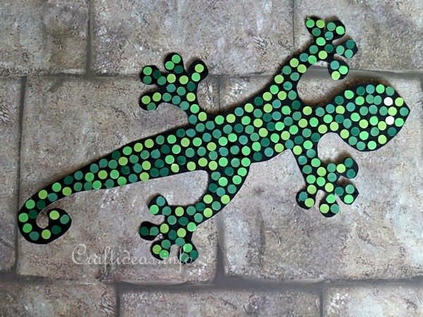 a green and black lizard sitting on top of a stone floor next to a brick wall