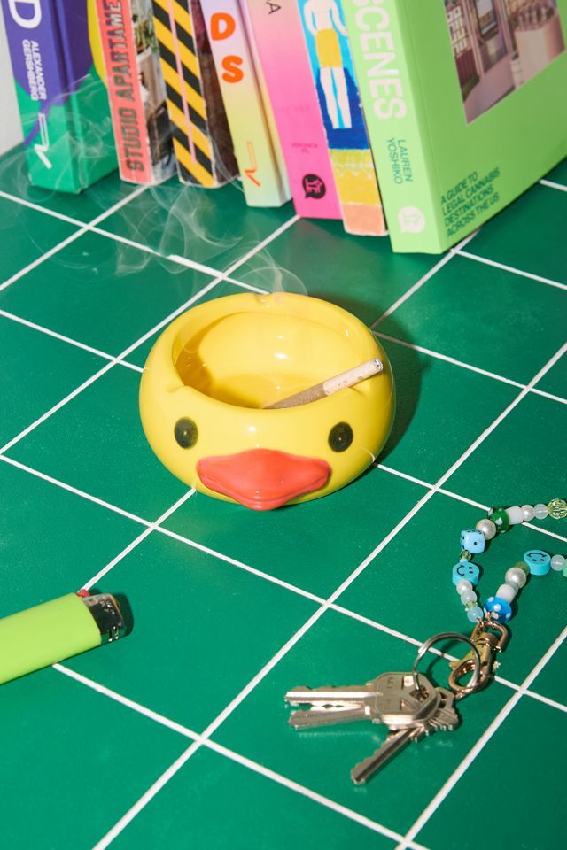 a yellow rubber duck sitting on top of a green tile floor next to a pair of scissors