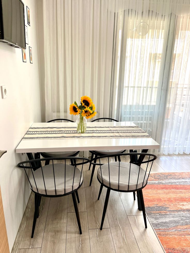 a dining table with four chairs and a vase filled with flowers on top of it