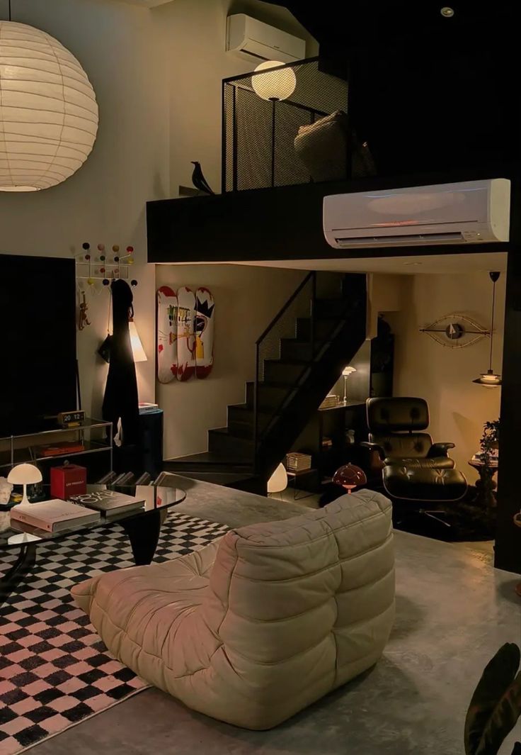 a living room with black and white checkered flooring in the foreground is a staircase leading up to an upper level loft